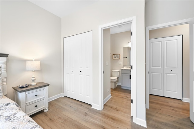 bedroom with ensuite bath, a closet, and light hardwood / wood-style flooring