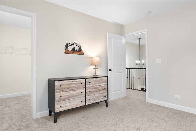 hallway with an inviting chandelier and light colored carpet