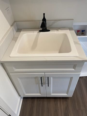 details with a tub, dark hardwood / wood-style floors, and sink