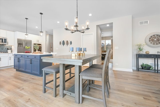 dining area with light hardwood / wood-style floors and an inviting chandelier