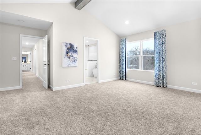 unfurnished bedroom featuring light carpet, ensuite bathroom, and vaulted ceiling with beams