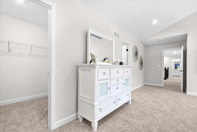 hallway featuring light colored carpet and lofted ceiling