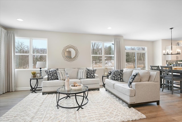 living room featuring plenty of natural light, a notable chandelier, and light wood-type flooring