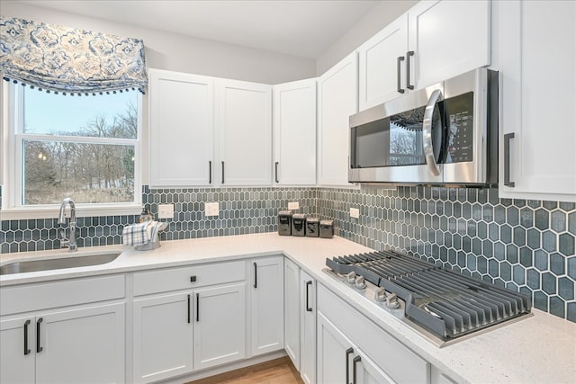 kitchen featuring appliances with stainless steel finishes, white cabinetry, tasteful backsplash, and sink