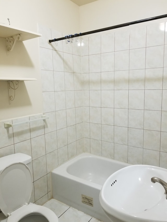 full bathroom with tile walls, toilet, sink, tiled shower / bath, and tile flooring