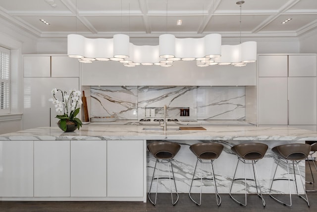 kitchen featuring tasteful backsplash, hanging light fixtures, white cabinets, and light stone counters