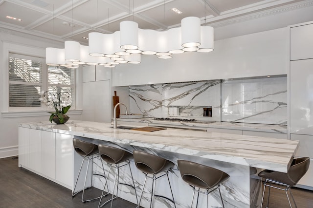 kitchen with decorative light fixtures, white cabinets, backsplash, and light stone counters