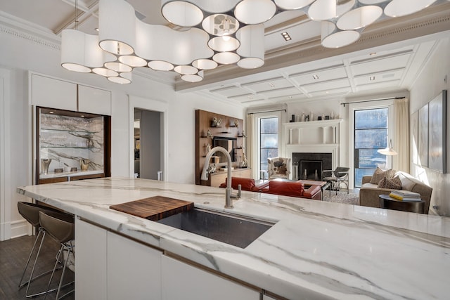 kitchen with coffered ceiling, white cabinets, dark hardwood / wood-style floors, and light stone countertops