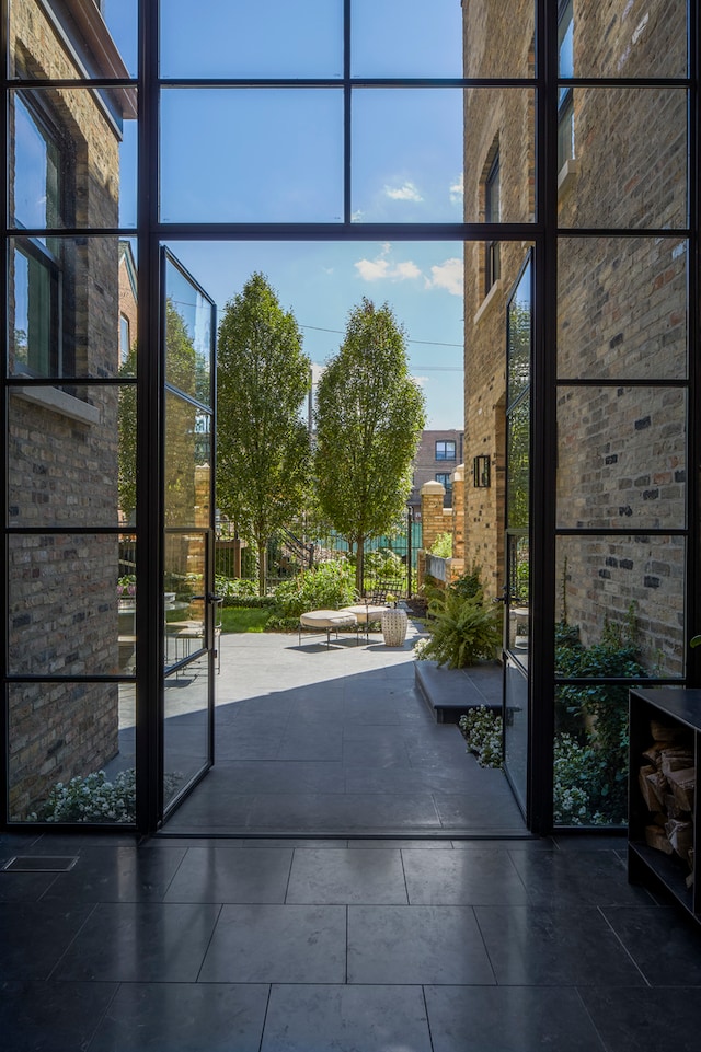 entryway with dark tile floors, expansive windows, and plenty of natural light