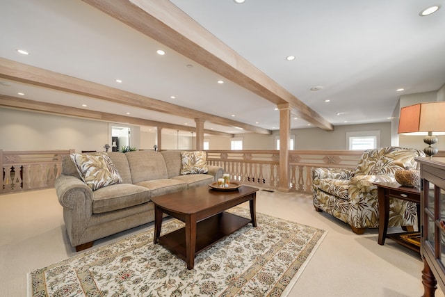 living room with beam ceiling, decorative columns, and light colored carpet