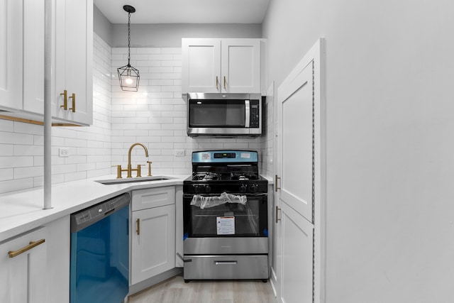 kitchen with pendant lighting, stainless steel appliances, sink, light hardwood / wood-style flooring, and white cabinets