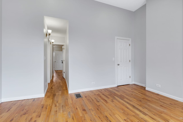 unfurnished room featuring a high ceiling and light wood-type flooring