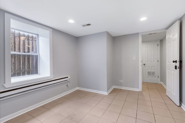 tiled spare room with a baseboard heating unit