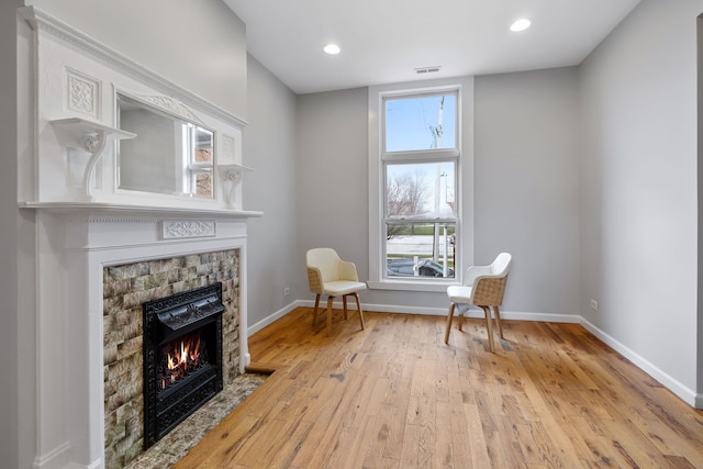 living area with light hardwood / wood-style flooring and a stone fireplace