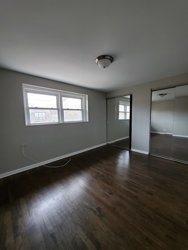 unfurnished bedroom with dark hardwood / wood-style floors and multiple windows