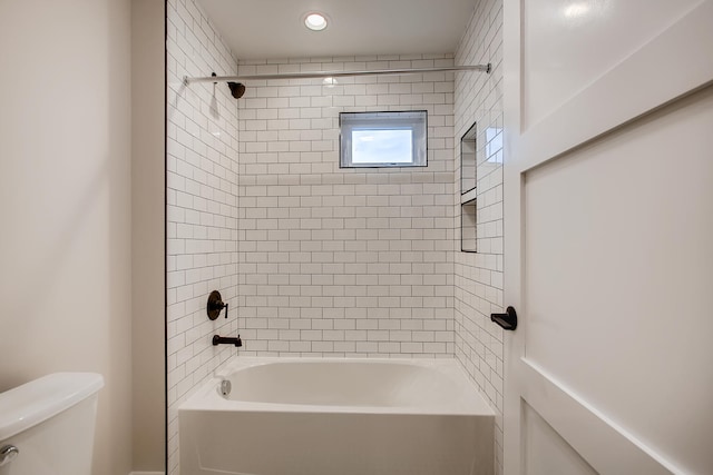 bathroom with toilet and tiled shower / bath combo