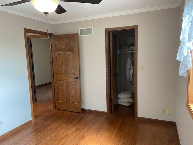 unfurnished bedroom with a closet, a spacious closet, ceiling fan, and hardwood / wood-style flooring