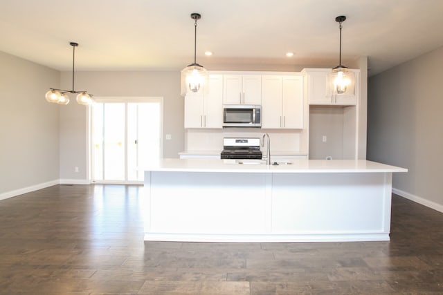 kitchen featuring white cabinetry, hanging light fixtures, and an island with sink