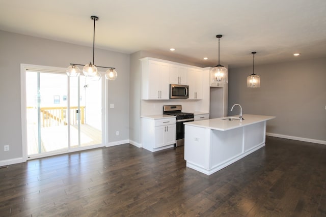 kitchen featuring hanging light fixtures, dark wood-type flooring, appliances with stainless steel finishes, and a kitchen island with sink