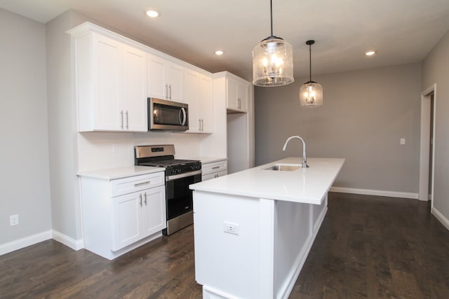 kitchen featuring an island with sink, appliances with stainless steel finishes, white cabinetry, dark hardwood / wood-style floors, and sink