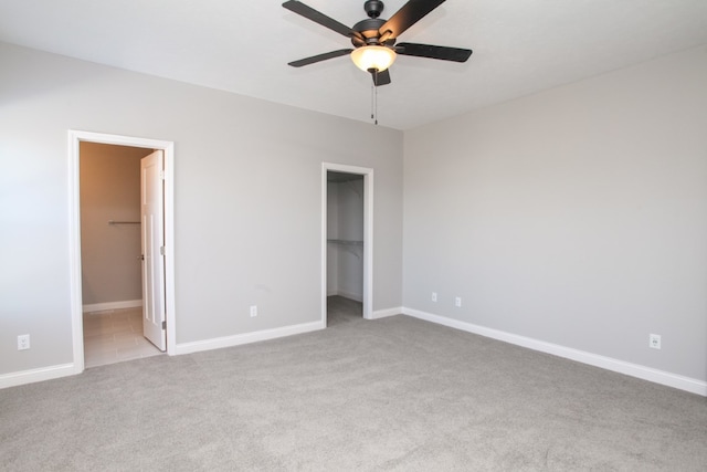 unfurnished bedroom featuring a spacious closet, light colored carpet, and ensuite bathroom