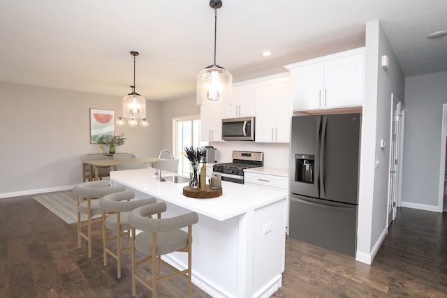 kitchen with white cabinetry, decorative light fixtures, dark wood-type flooring, a kitchen island with sink, and stainless steel appliances