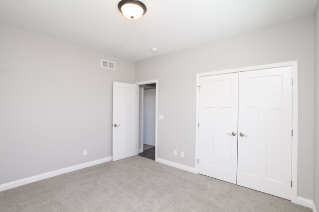 unfurnished bedroom featuring light colored carpet and a closet