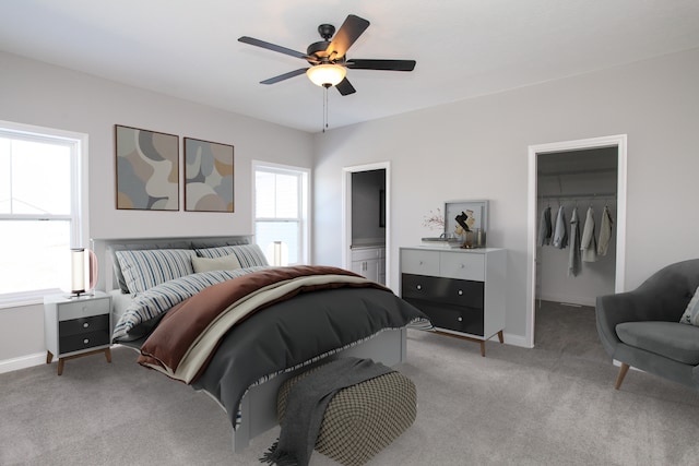 carpeted bedroom featuring ensuite bathroom, a closet, a walk in closet, and ceiling fan