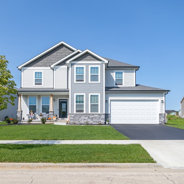 view of front of property with a porch, a front lawn, and a garage