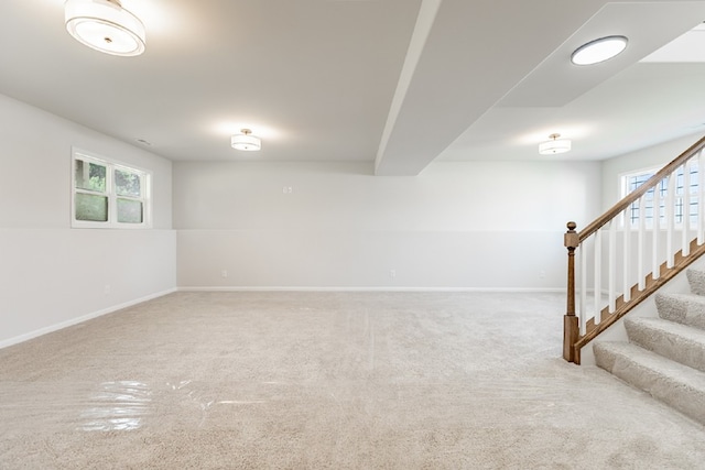 below grade area with carpet, a healthy amount of sunlight, stairway, and baseboards