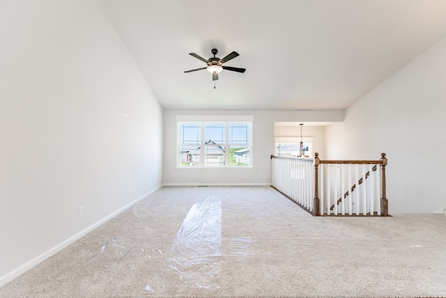 carpeted spare room with baseboards and ceiling fan with notable chandelier