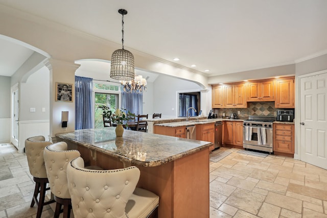 kitchen featuring kitchen peninsula, decorative light fixtures, an inviting chandelier, appliances with stainless steel finishes, and a breakfast bar