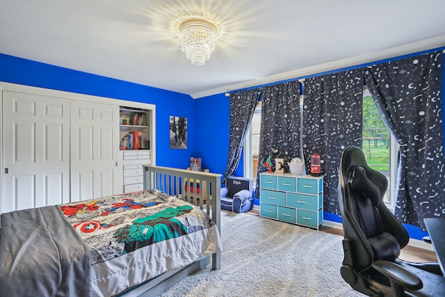 carpeted bedroom with a closet and a chandelier