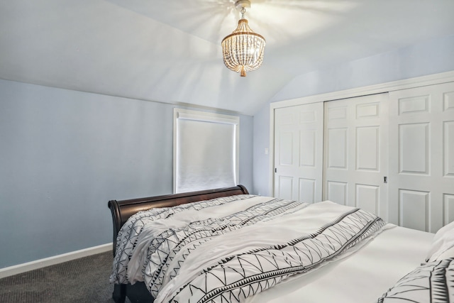 bedroom with dark colored carpet, a closet, a chandelier, and lofted ceiling