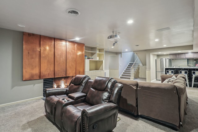 carpeted cinema room featuring bar area and a fireplace