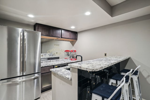 kitchen with stainless steel fridge, dark brown cabinets, light wood-type flooring, a kitchen bar, and a center island