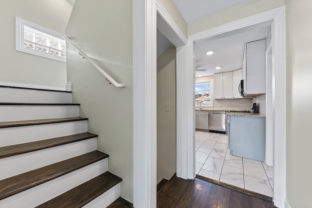 stairs featuring a healthy amount of sunlight, light tile floors, and sink