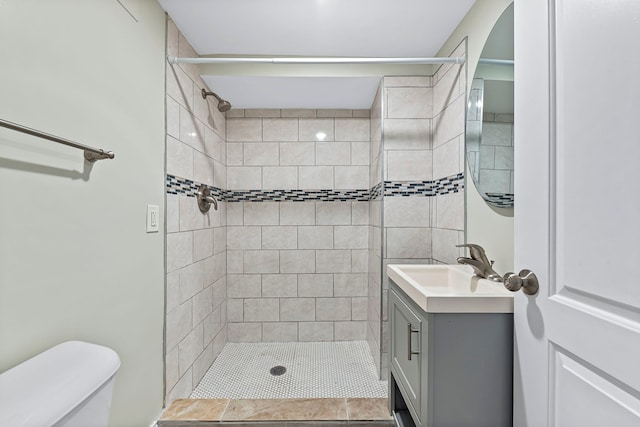 bathroom with tiled shower, toilet, and vanity