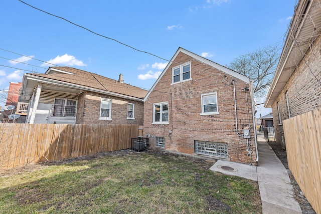 back of property featuring central AC unit and a yard