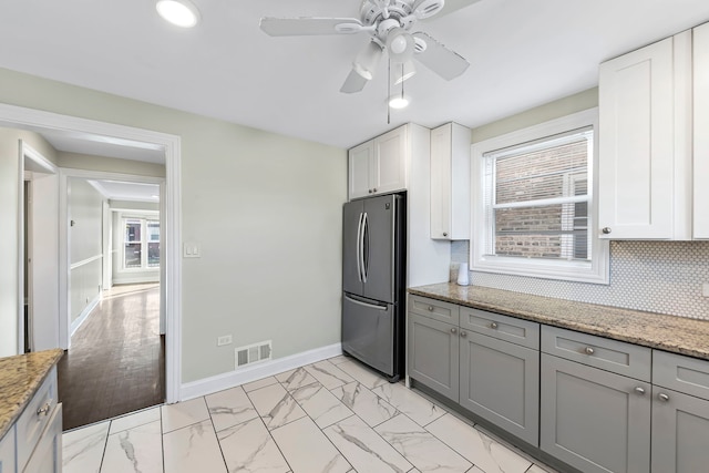 kitchen featuring ceiling fan, stainless steel fridge, light wood-type flooring, and a healthy amount of sunlight