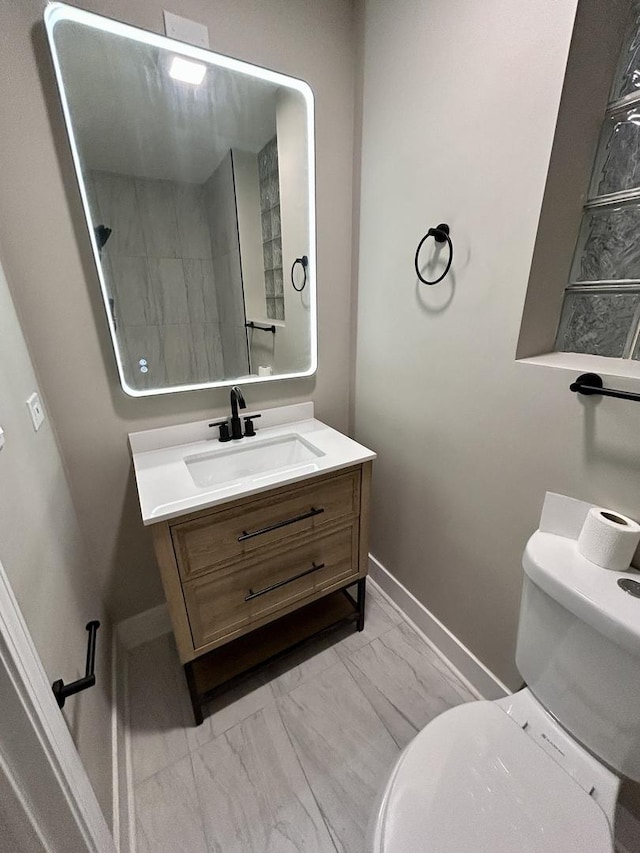bathroom featuring vanity, marble finish floor, baseboards, and toilet