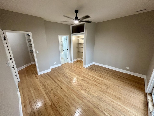 unfurnished bedroom with a closet, ensuite bath, a spacious closet, visible vents, and light wood finished floors