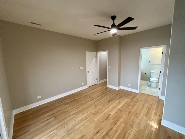 unfurnished bedroom with light wood finished floors, visible vents, baseboards, and connected bathroom