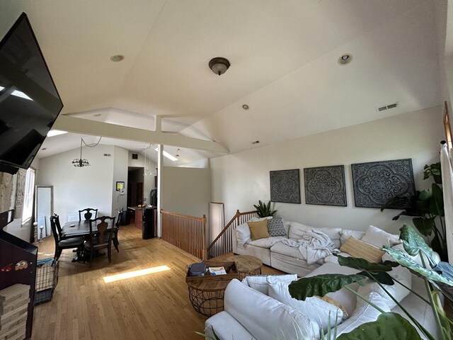 living area with visible vents, wood finished floors, and lofted ceiling