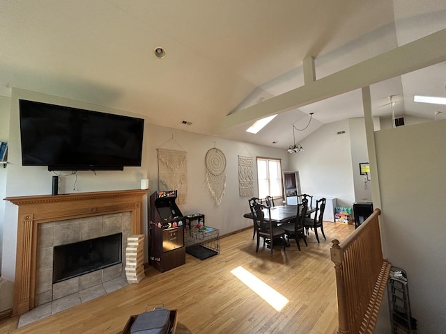living area featuring visible vents, a tile fireplace, wood finished floors, and lofted ceiling