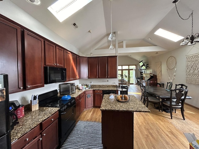 kitchen featuring vaulted ceiling with skylight, a center island, light wood-style floors, visible vents, and black appliances