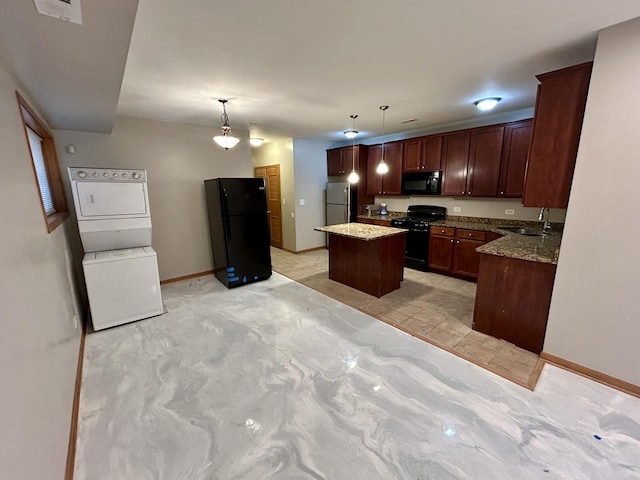 kitchen featuring baseboards, stacked washer and dryer, a center island, black appliances, and a sink