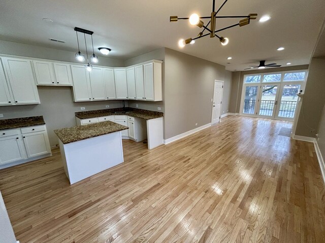 kitchen with white cabinets, open floor plan, baseboards, and light wood-type flooring