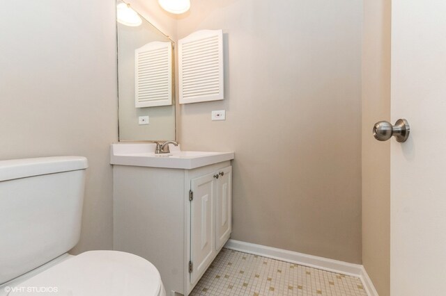 bathroom with tile flooring, toilet, and vanity