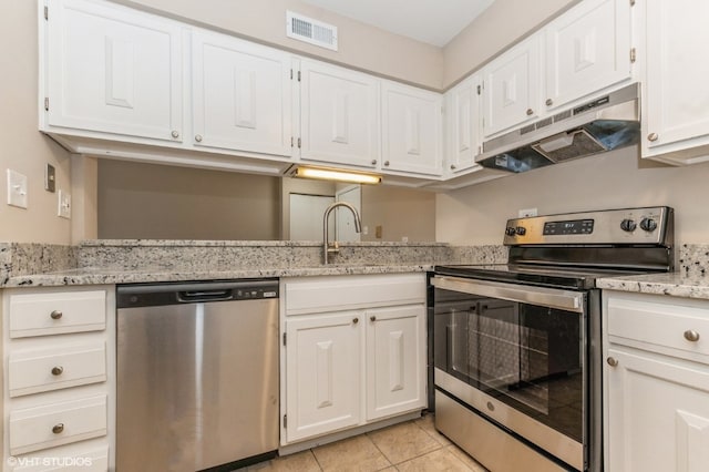 kitchen featuring appliances with stainless steel finishes, light stone counters, white cabinets, and light tile flooring